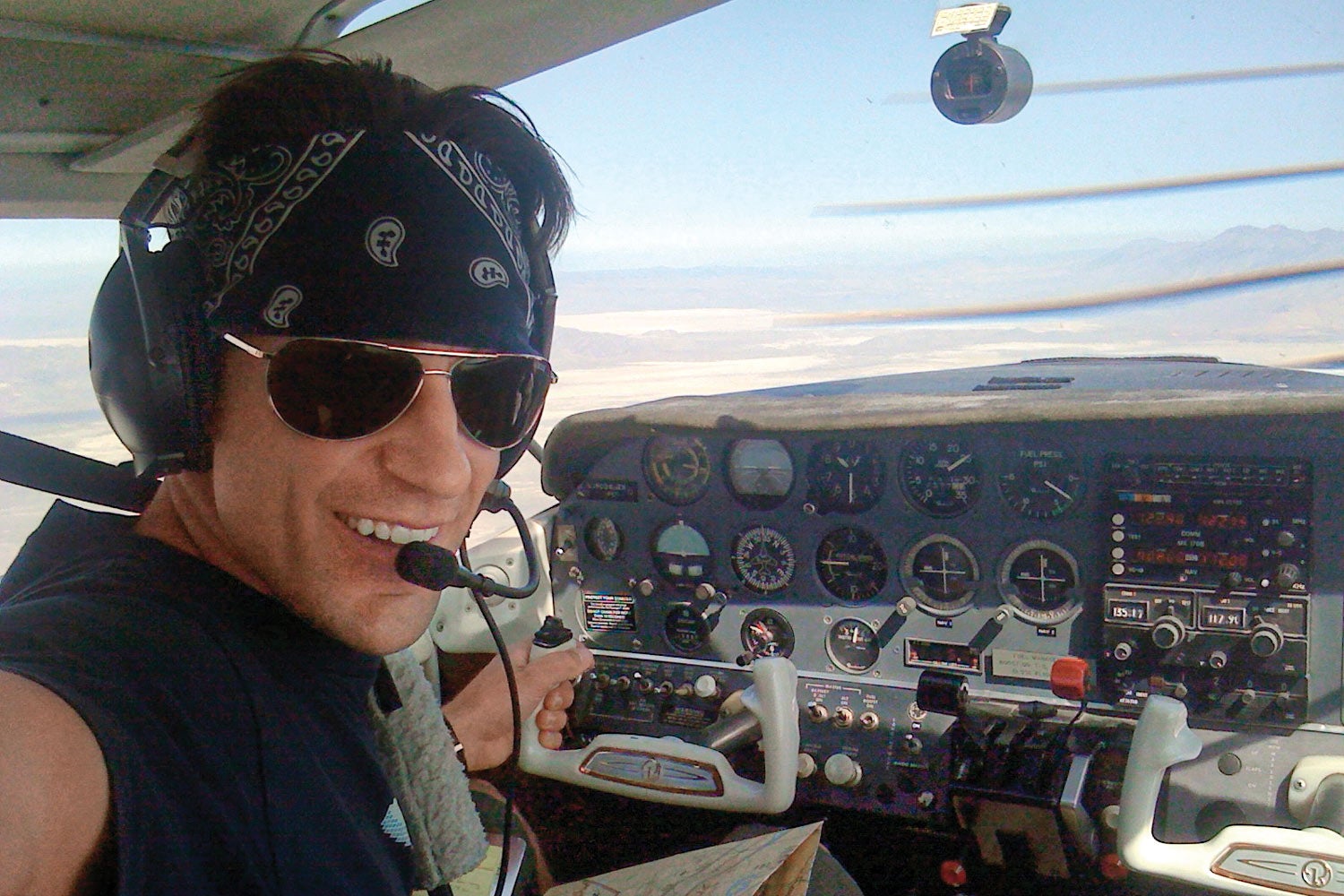 man looking at camera while flying an airplane