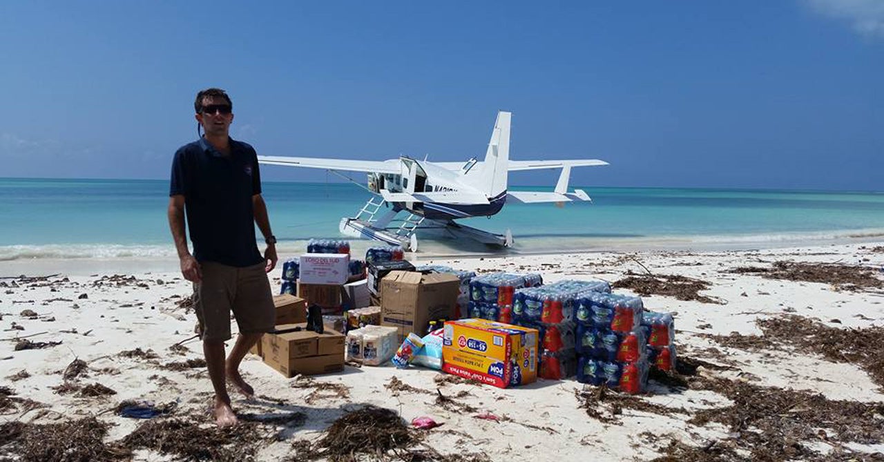 man on beach next to supplies with seaplane in background