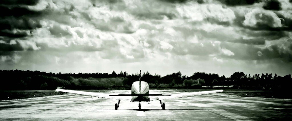 An airplane on a tarmac with threatening clouds in the sky