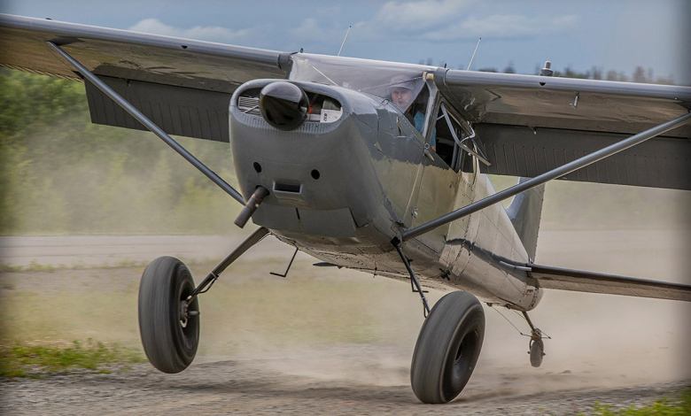 An airplane lands on a dirt strip in the backcountry