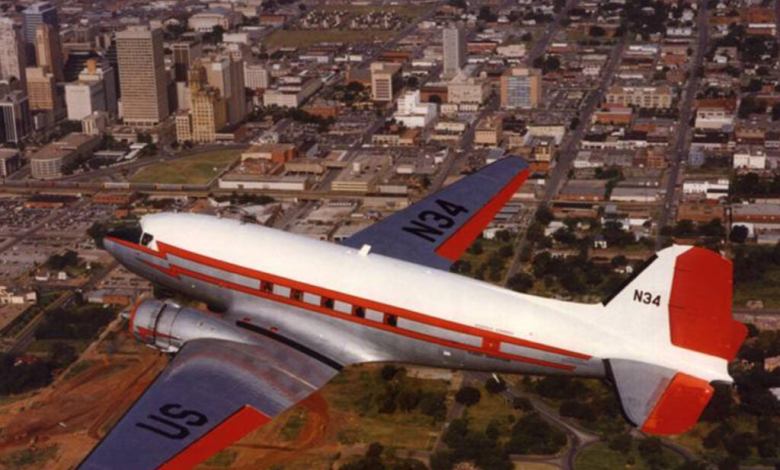 A DC-3 soars the skies over a city