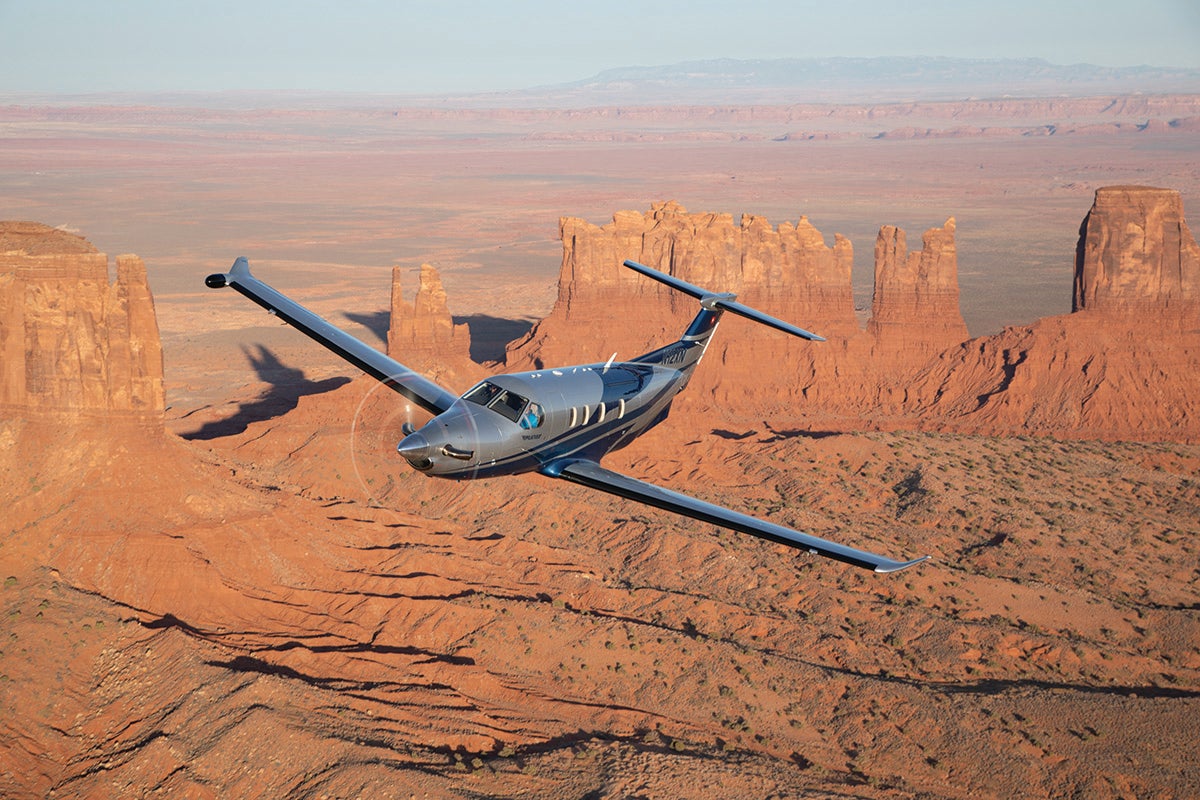 The Pilatus PC-12 aircraft soars over Monument Valley.