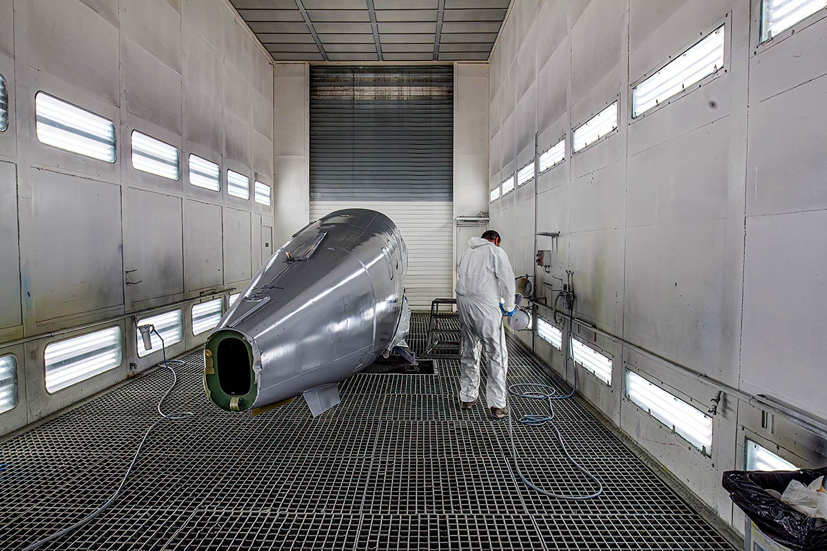A man in a white safety suit works on the fuselage of a Daher TBM 960 under construction.
