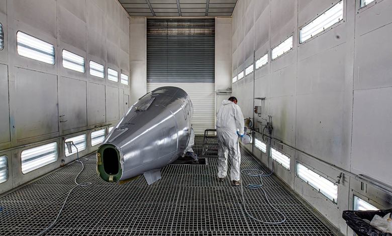 A man in a white safety suit works on the fuselage of a Daher TBM 960 under construction.