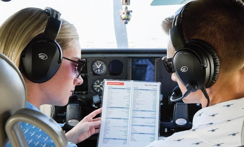 Two aviators in a cockpit looking over a checklist