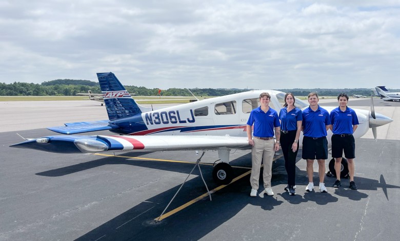 ATP Flight School students standing beside a Piper Archer training aircraft on the tarmac, wearing blue ATP uniforms, preparing for pilot training.