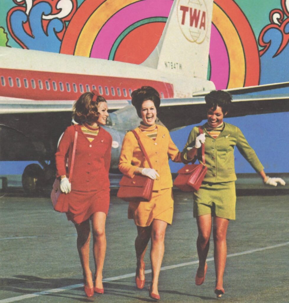 Three flight attendants wear their TWA uniforms for a flight attendant recruiting brochure which declares, 'Be a Woman of the World.' [Credit: Museum of Flight]