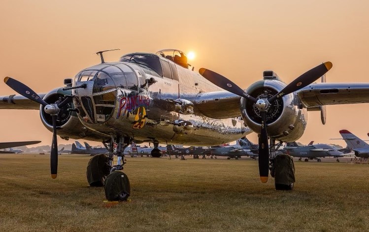 A B-25 sits parked against the backdrop of smoke-filled skies at AirVenture in 2024. [Credit: Meg Godlewski]