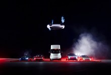 Tesla flying Roadster inverted over a row of other vehicles
