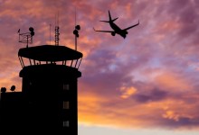 Silhouette of air traffic control (ATC) tower during sunset with airplane flying overhead