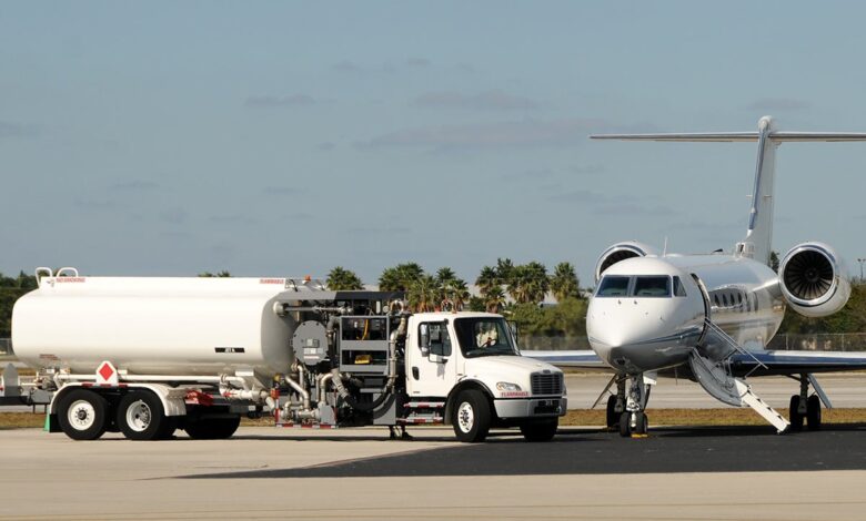 A business jet parked next to a refueling truck