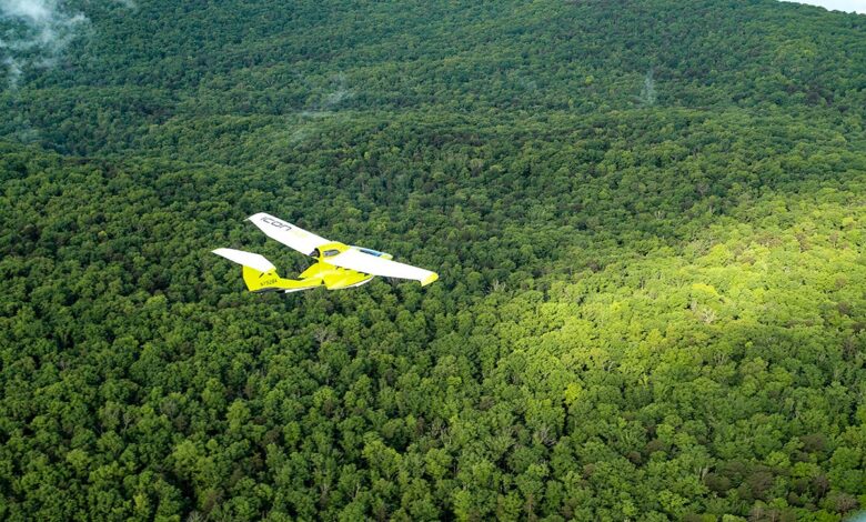 An Icon A5 aircraft flies over the treetops along the Sequatchie Valley.