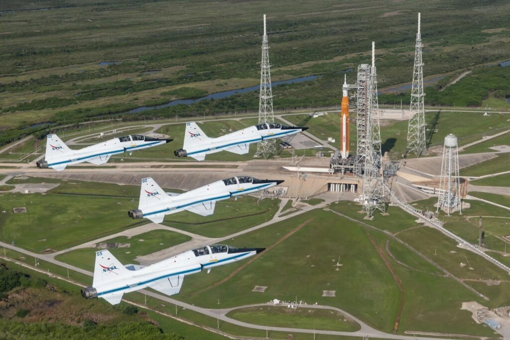 NASA T-38 Talon trainer aircraft fly in formation over SLS at Kennedy Space Center in Florida